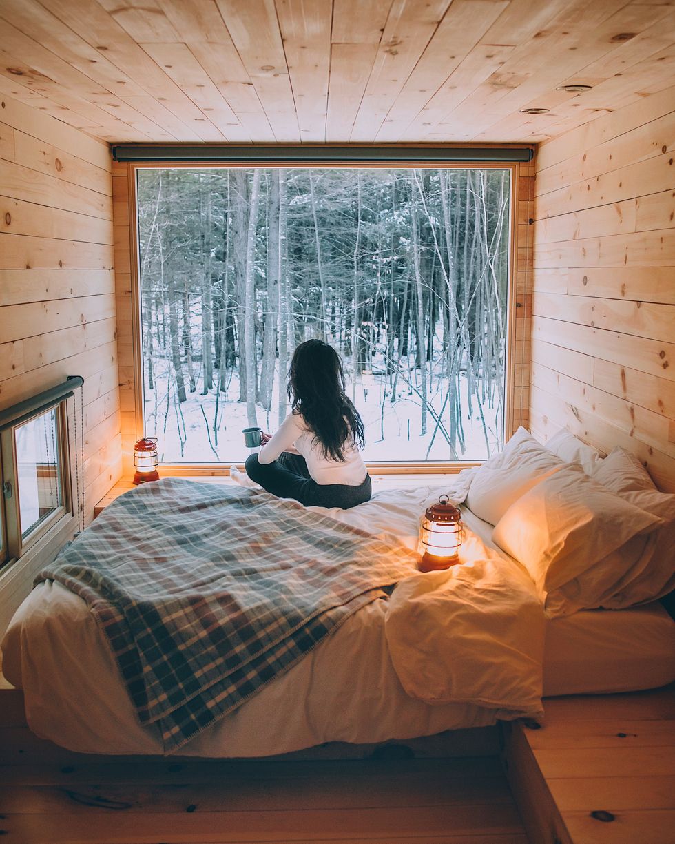 Woman in bed, looking out a snowy window