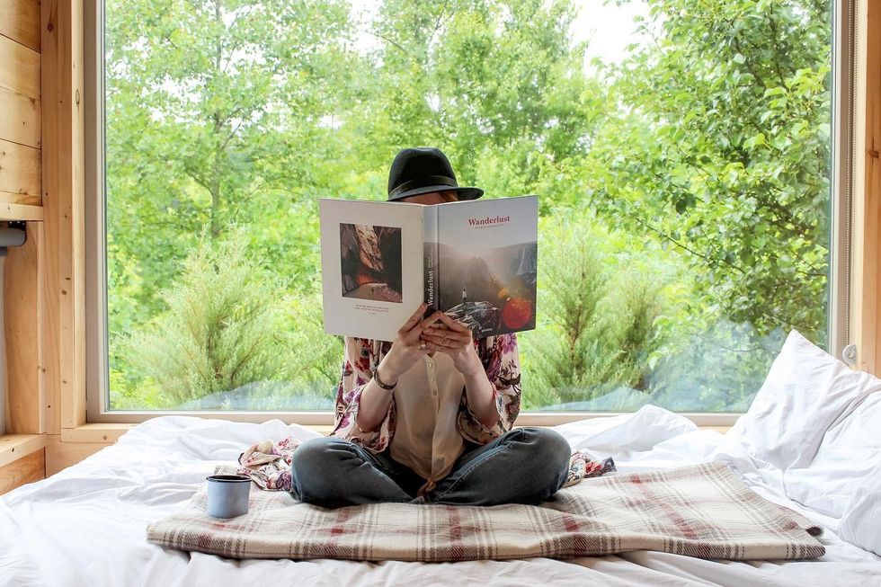 Woman in a bed with books at a getaway cabin.